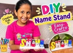 A girl holding a painted DIY name stand that spells her name